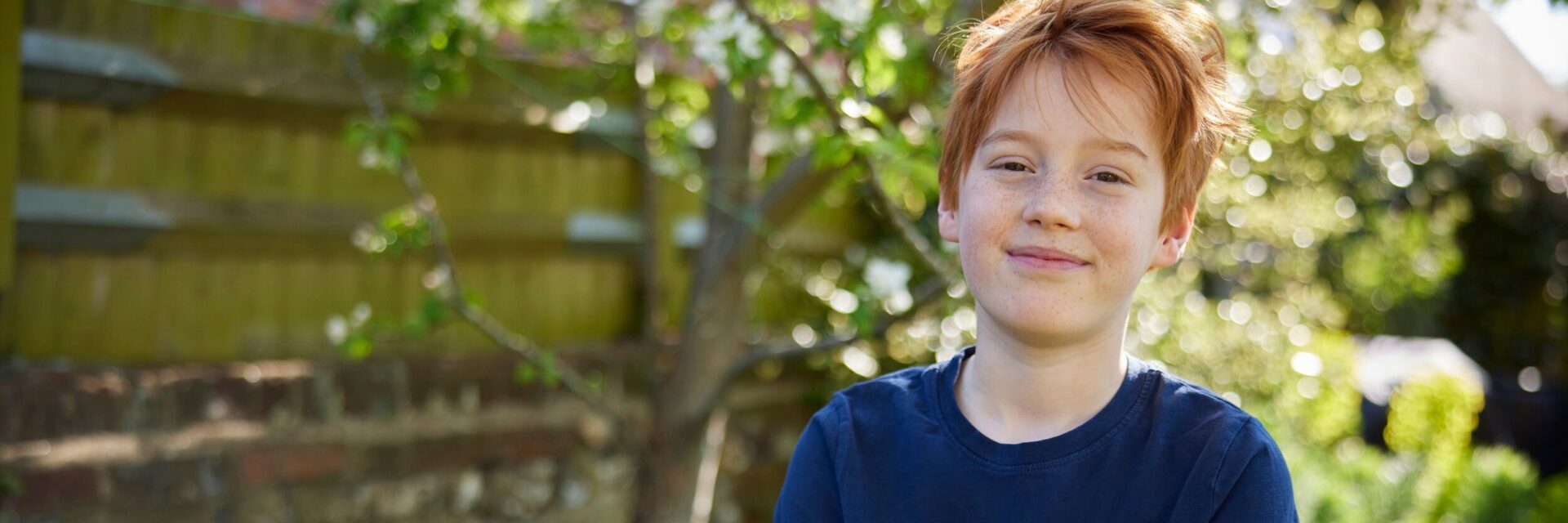 Boy standing with his arms folded in the garden