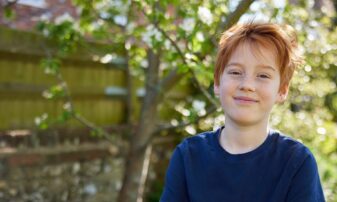 Boy standing with his arms folded in the garden