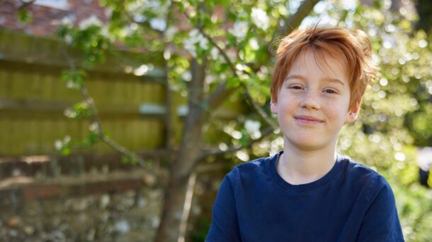 Boy standing with his arms folded in the garden