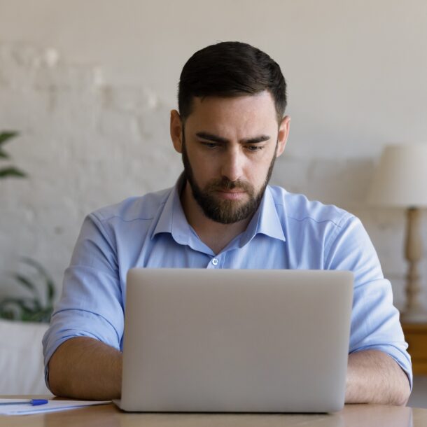 Man sat at a table working on a laptop