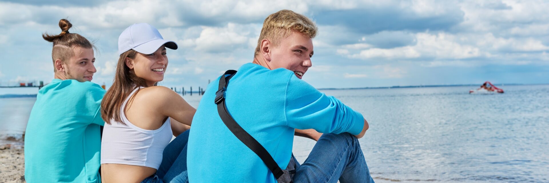 Three teenagers sat on the beach