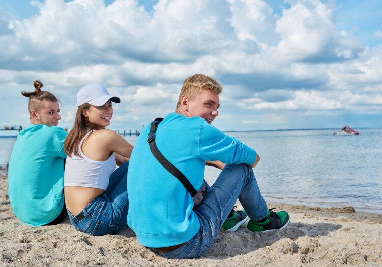 Three teenagers sat on the beach